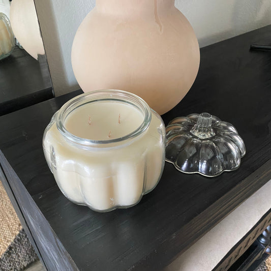 A glass pumpkin candle with the lid off